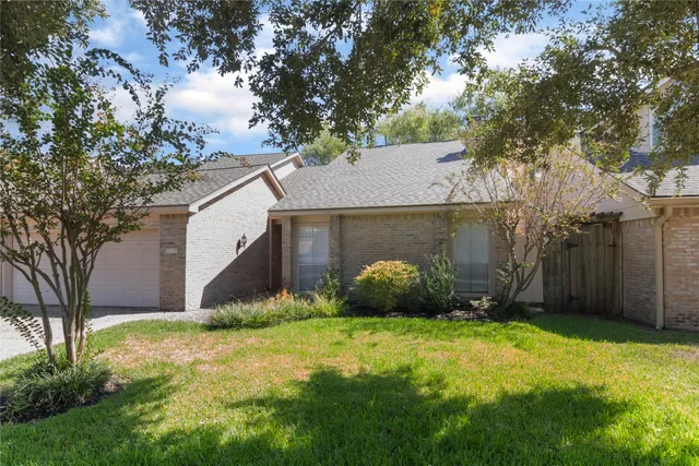 a view of a house with potted plants and a large tree