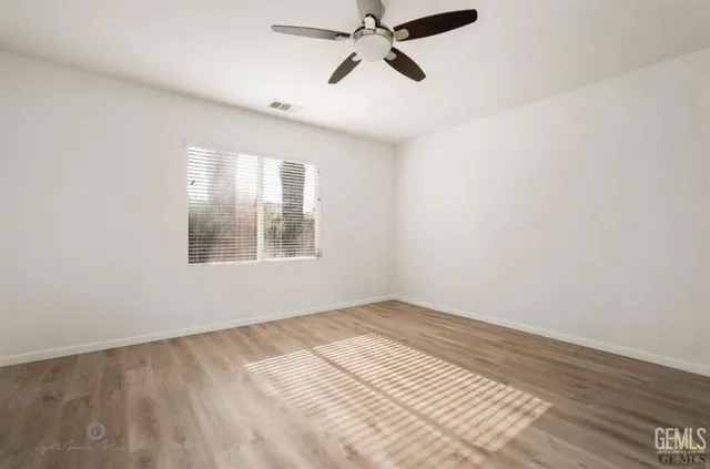 a view of empty room with wooden floor and fan