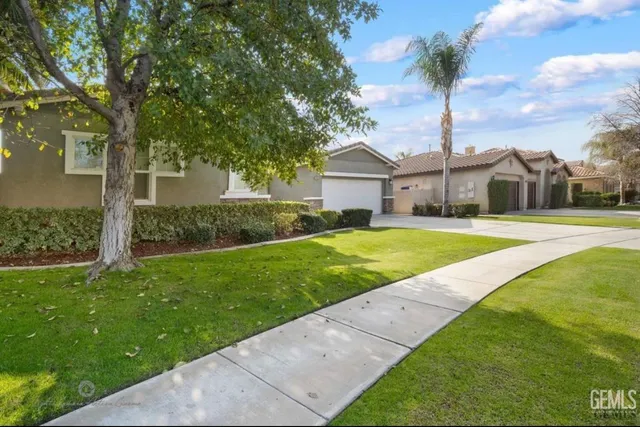 a front view of a house with a yard and palm trees