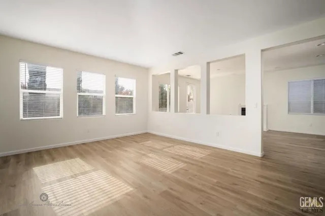 a view of an empty room with wooden floor and windows