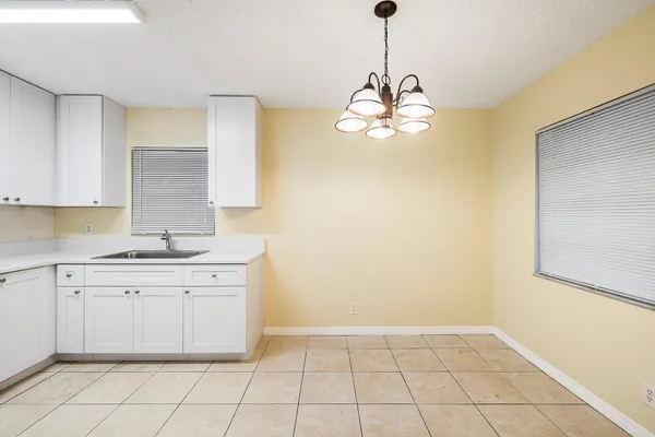 a very nice looking kitchen with a sink cabinetry and a chandelier