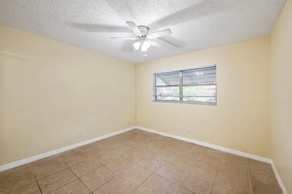 an empty room with windows and fan