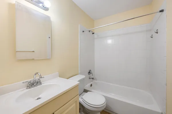 a bathroom with a bathtub shower sink vanity mirror and toilet