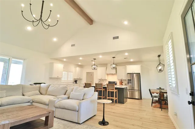 a living room with furniture kitchen view and a wooden floor