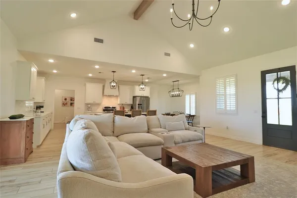 a living room with couches and kitchen view with wooden floor
