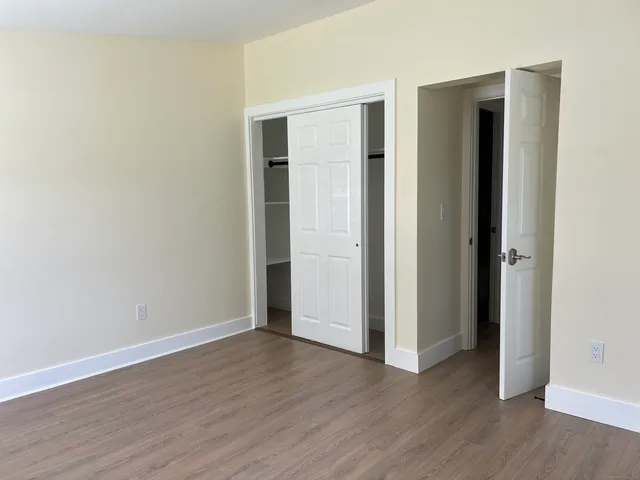 an empty room with wooden floor & closet and windows
