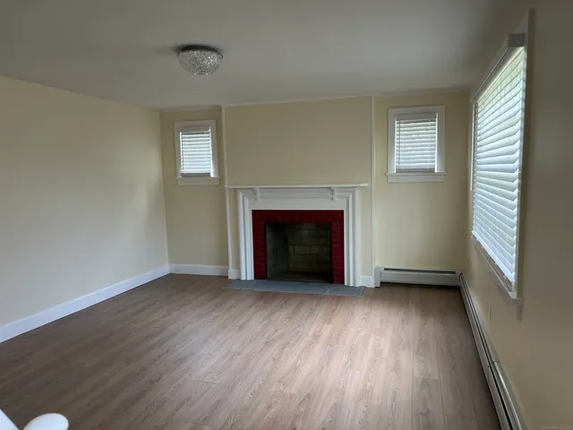 an empty room with wooden floor fireplace and windows
