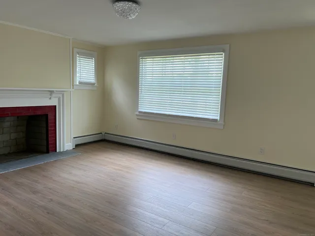 an empty room with wooden floor fireplace and windows