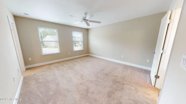 an empty room with windows and chandelier fan