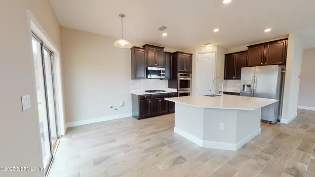 a large kitchen with stainless steel appliances kitchen island a large counter top a stove and a refrigerator