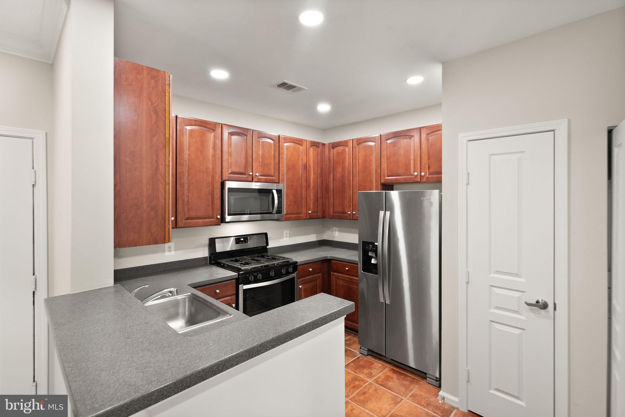 12001 Market Street, Unit 206 Reston, VA 20190 - Photo 7 of 25 a kitchen with stainless steel appliances granite countertop a refrigerator stove and sink