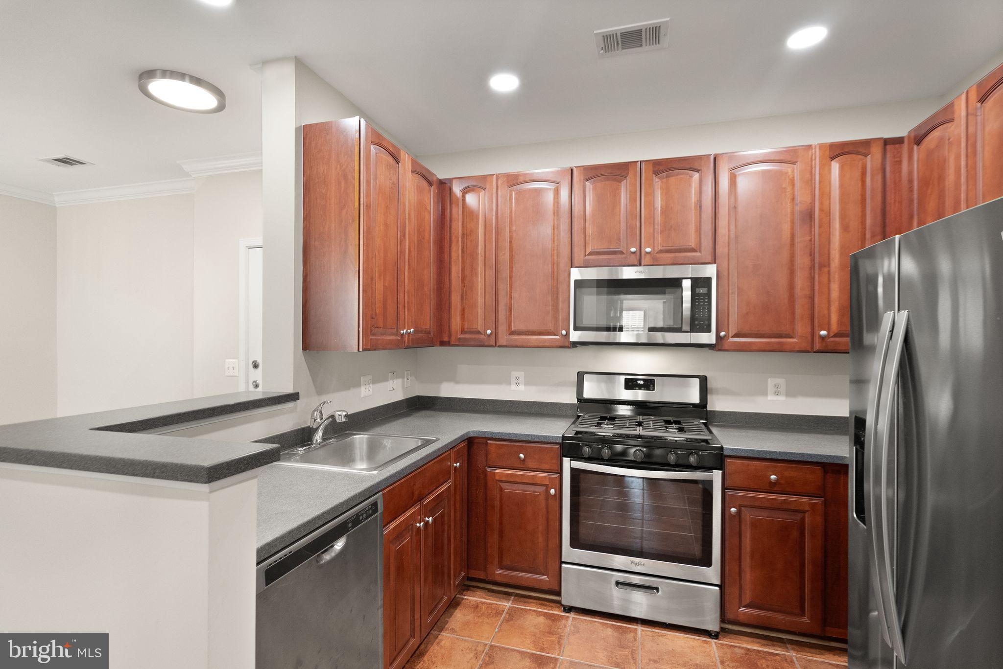 12001 Market Street, Unit 206 Reston, VA 20190 - Photo 9 of 25 a kitchen with granite countertop stainless steel appliances and wooden cabinets