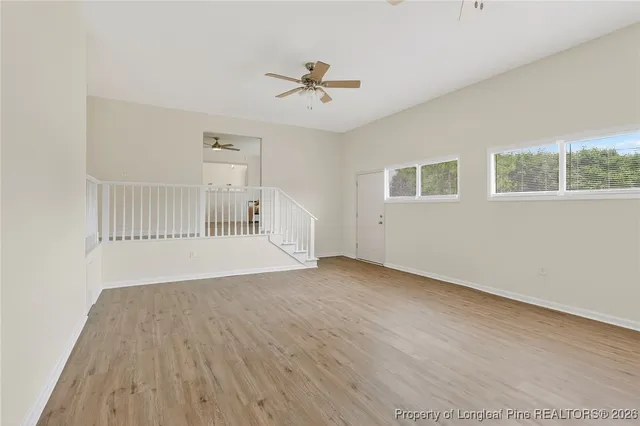 a view of an empty room with a window and wooden floor