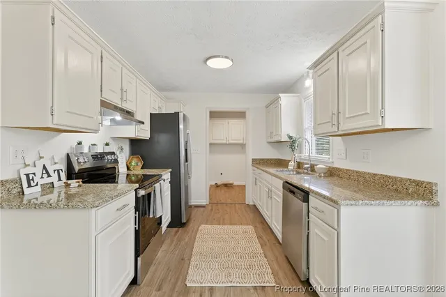 a kitchen with stainless steel appliances granite countertop a stove top oven a sink dishwasher and a refrigerator
