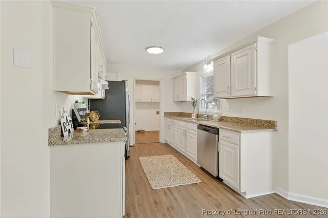 a kitchen with granite countertop white cabinets and white appliances