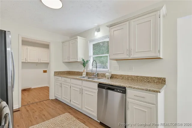 a kitchen with stainless steel appliances granite countertop a sink and dishwasher with white cabinets
