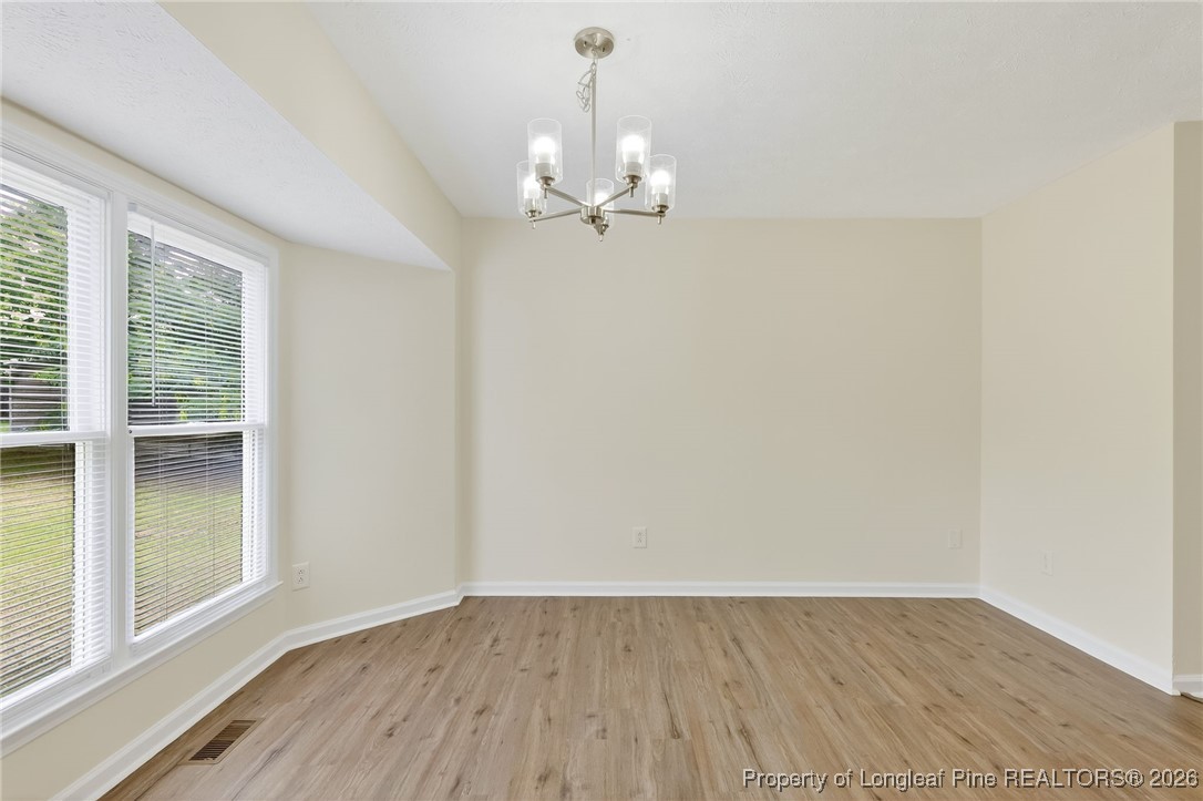 6250 Waldos Beach Road Fayetteville, NC 28306 - Photo 27 of 50 an empty room with wooden floor chandelier fan and windows