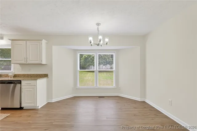an empty room with wooden floor cabinets and a window