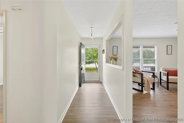 a view of a hallway with furniture and wooden floor