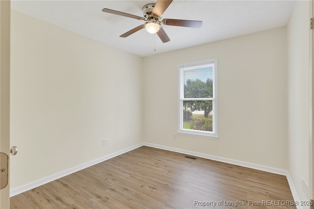 6250 Waldos Beach Road Fayetteville, NC 28306 - Photo 31 of 50 an empty room with wooden floor ceiling fan and windows