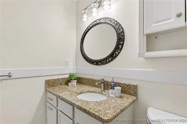a bathroom with a granite countertop toilet a sink and a mirror