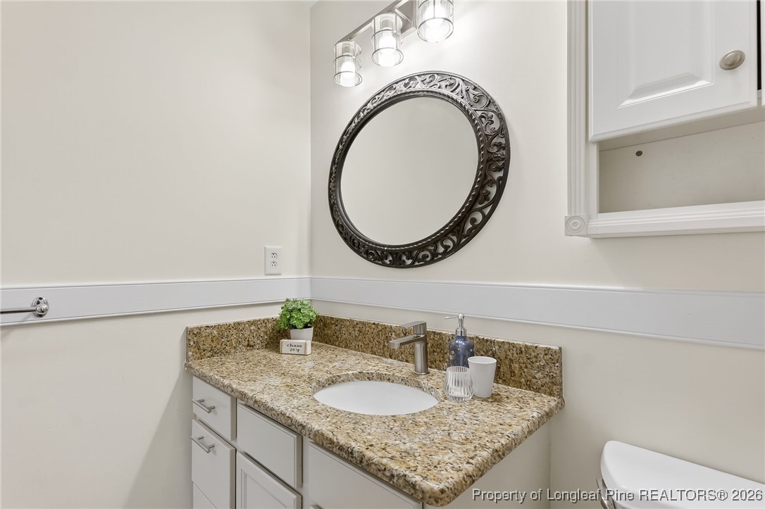6250 Waldos Beach Road Fayetteville, NC 28306 - Photo 33 of 50 a bathroom with a granite countertop toilet a sink and a mirror