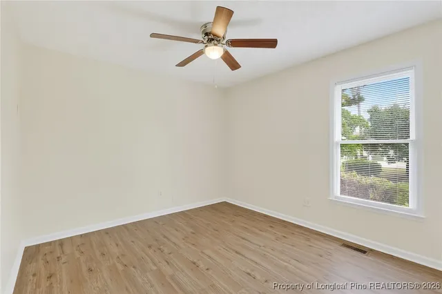 a view of empty room with wooden floor and fan