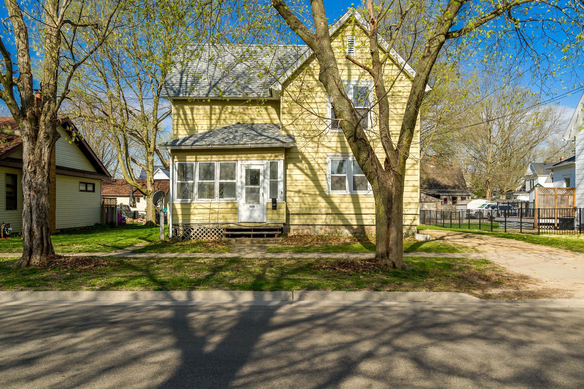 a view of a yard in front of a house with a large tree