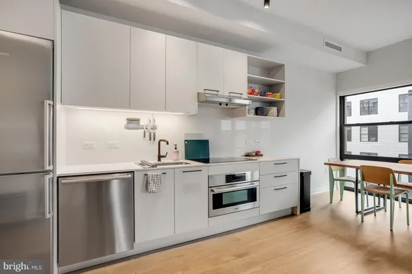 a kitchen with stainless steel appliances a refrigerator a stove and white cabinets