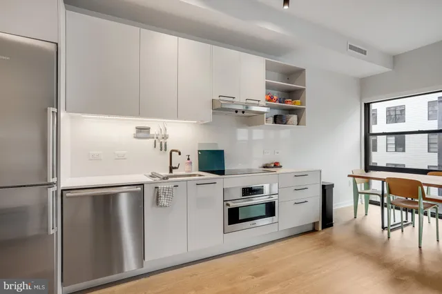 a kitchen with stainless steel appliances a refrigerator a stove and white cabinets