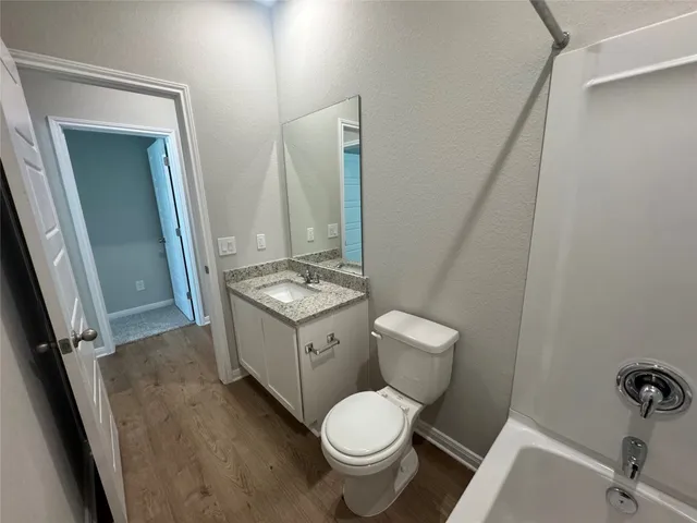a bathroom with a granite countertop sink toilet a mirror and shower