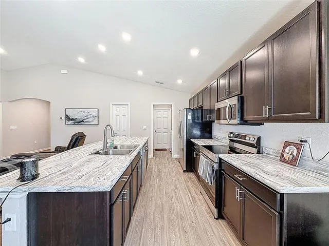 a large kitchen with stainless steel appliances granite countertop a lot of counter space and wooden floor