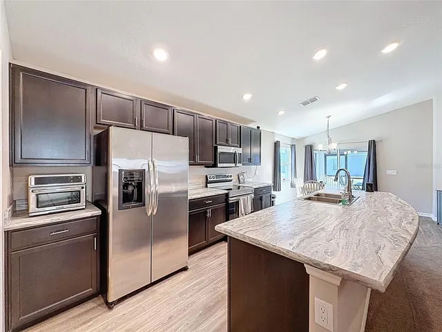 a kitchen with granite countertop a refrigerator and a stove top oven