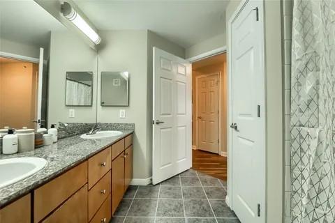 a bathroom with a granite countertop sink a toilet a mirror and shower curtain