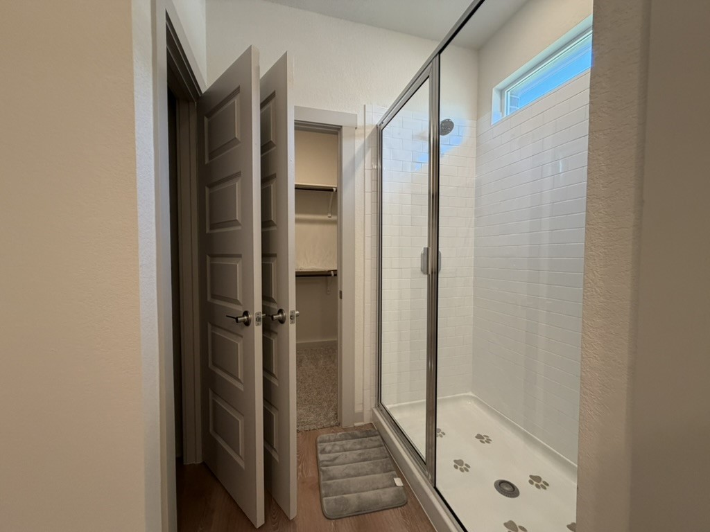 10708 Gonzales Ranger Pass Austin, TX 78754 - Photo 29 of 40 A well-lit shower enclosure with tiled walls and a charming paw print-adorned floor awaits within this clean bathroom.