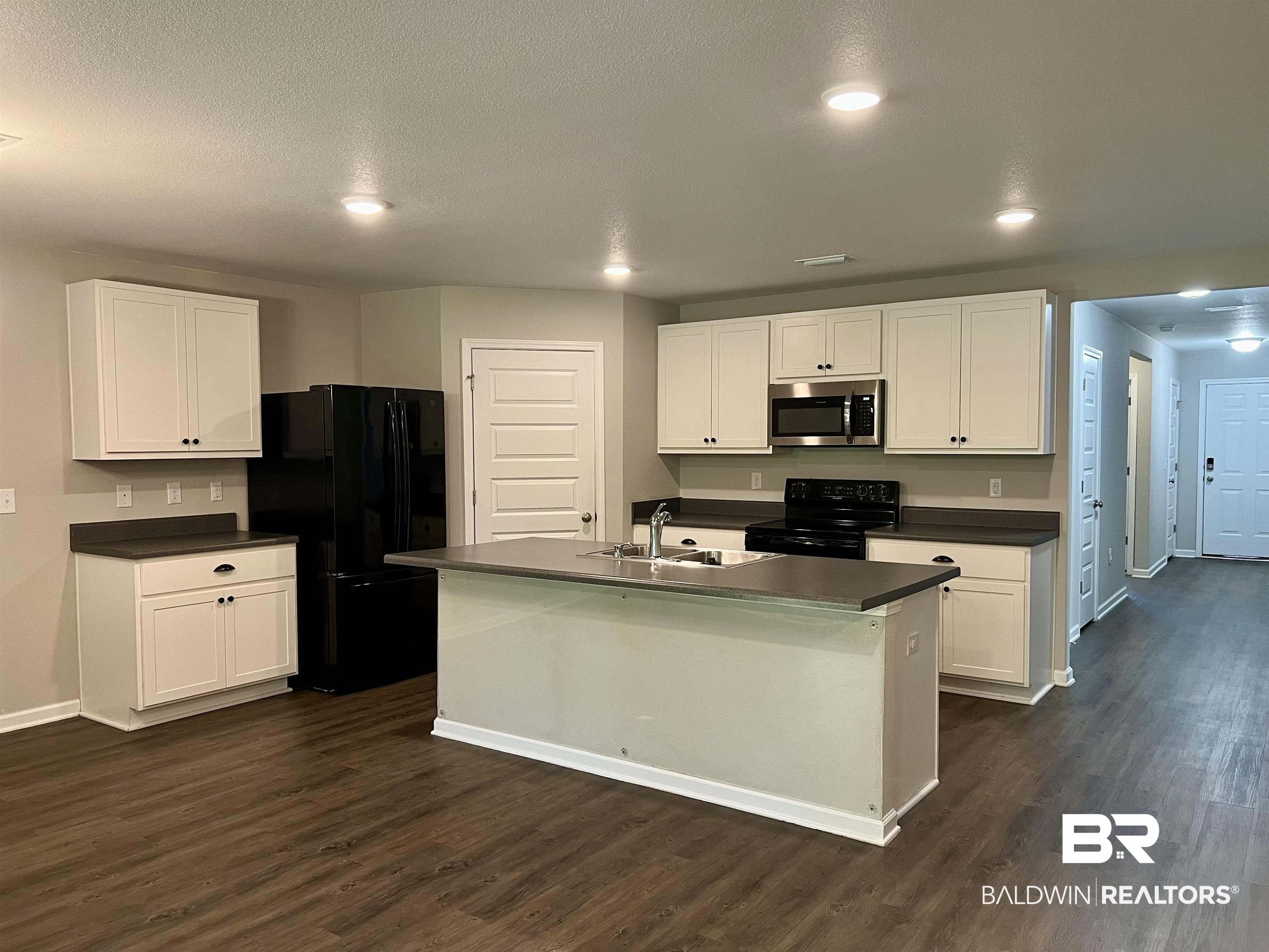 1612 Abbey Loop Foley, AL 36535 - Photo 13 of 30 Kitchen with dark hardwood / wood-style flooring, white cabinetry, black appliances, and a kitchen island with sink
