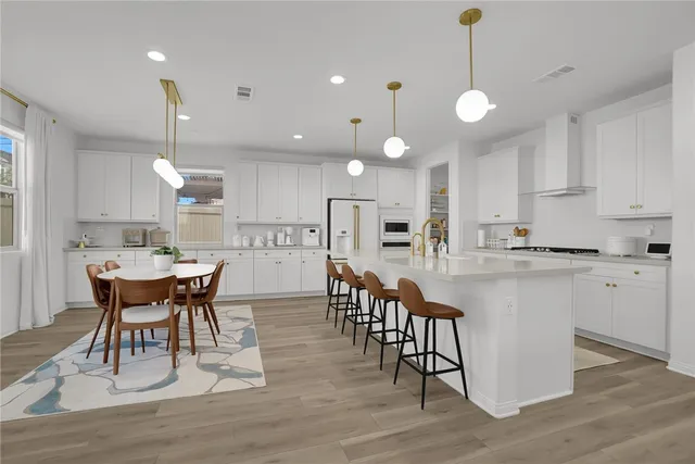 a kitchen with stainless steel appliances granite countertop a dining table chairs stove refrigerator and cabinets