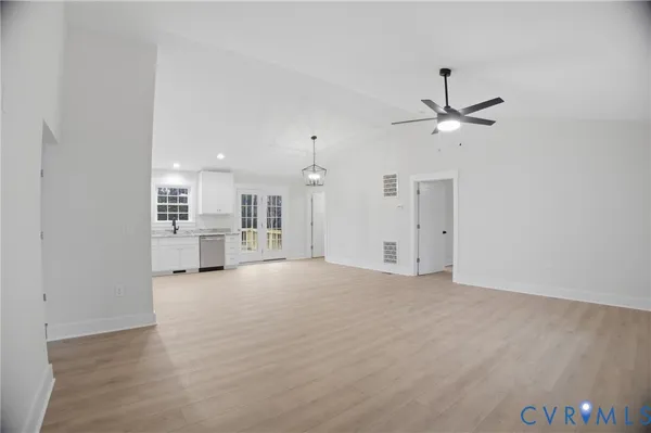 an empty room with chandelier fan and windows