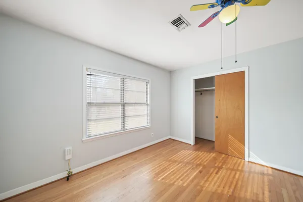 a view of empty room with wooden floor and fan