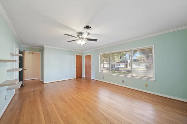 a view of an empty room with a window and wooden floor