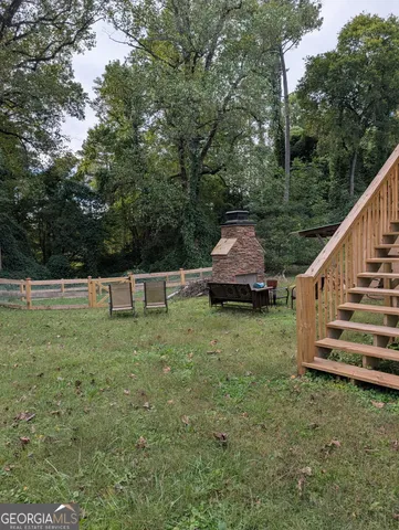a view of a backyard with wooden fence and large trees