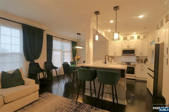 a kitchen with stainless steel appliances kitchen island granite countertop a refrigerator a stove a sink dishwasher a dining table and chairs with wooden floor