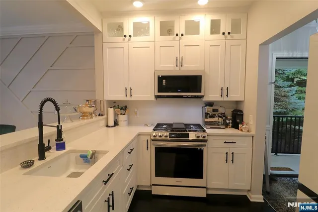 a kitchen with stainless steel appliances granite countertop a sink a stove and a microwave