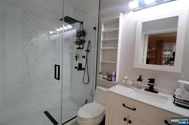 a bathroom with a granite countertop sink a toilet a mirror and shower
