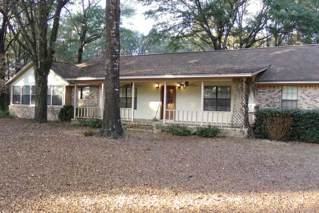 3845 Poverty Creek Road Crestview, FL 32539 - Photo 2 of 32 a view of a brick house with large windows and a large tree