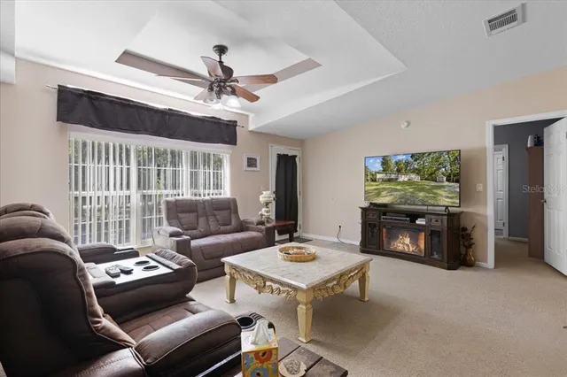 a living room with furniture a ceiling fan and a flat screen tv