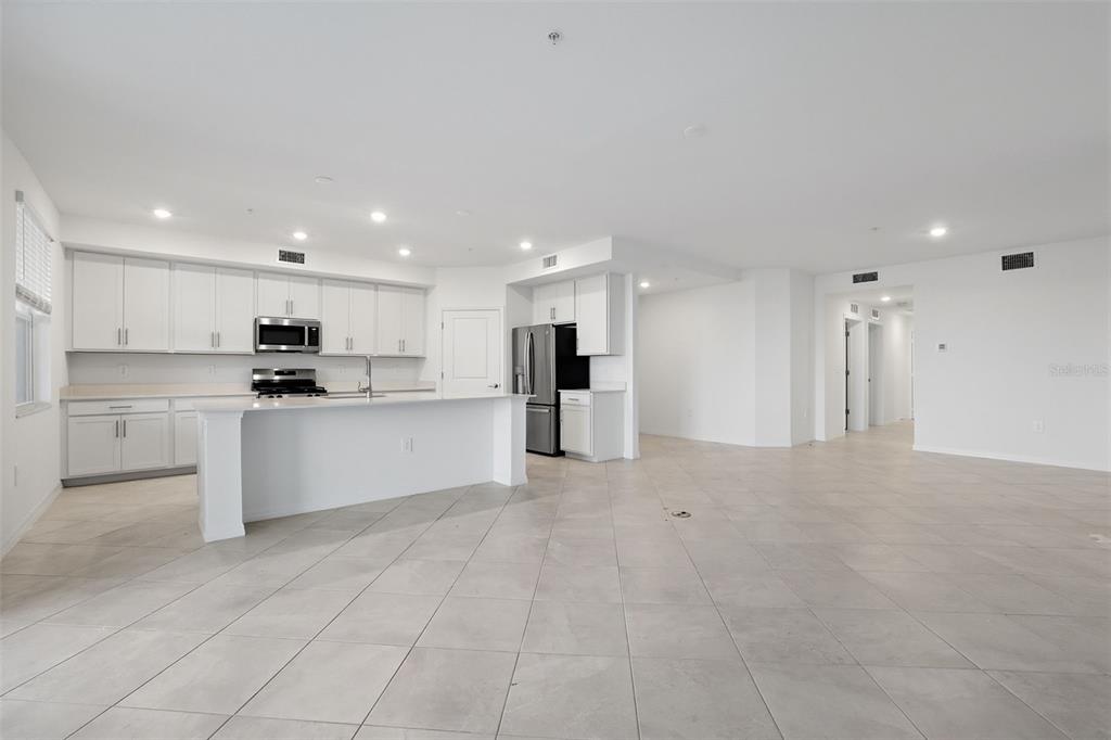 19219 Cherrystone Way, Unit 101 Lakewood Ranch, FL 34211 - Photo 3 of 19 a large white kitchen with kitchen island a sink a stove a refrigerator and white cabinets