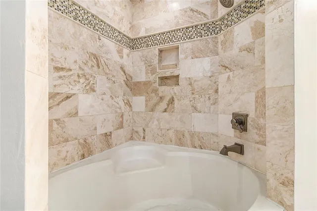 a bathroom with a granite countertop bathtub a sink and a mirror