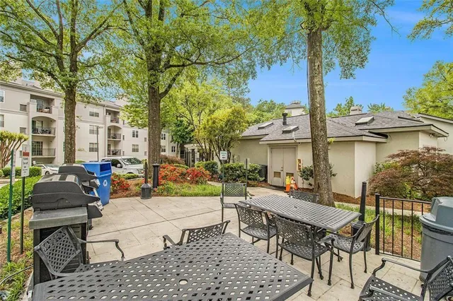 a view of a patio with table and chairs potted plants and large tree