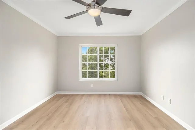 an empty room with wooden floor and ceiling fan